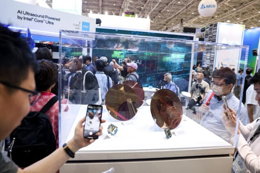 Visitors take pictures of wafer samples at the Intel booth during Computex 2024 in Taipei
