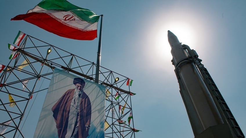 ayatollah shown on banner with Iran flag flying over it