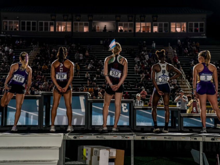 Sadie Schreiner, C, wears a transgender flag in her hair on the awards stand after finishi