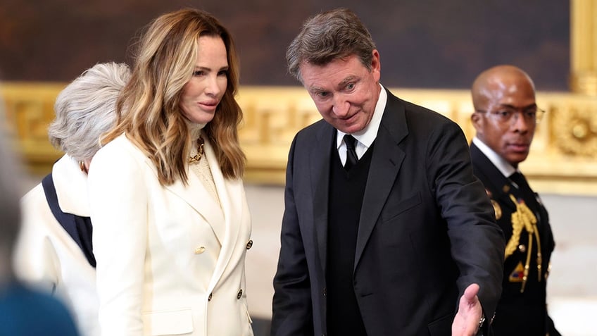 Janet Jones in a cream jacket stands beside husband Wayne Gretzky in the Capitol