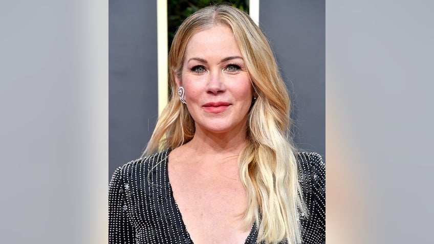 Christina Applegate in a plunging black dress with sparkles soft smiles on the carpet