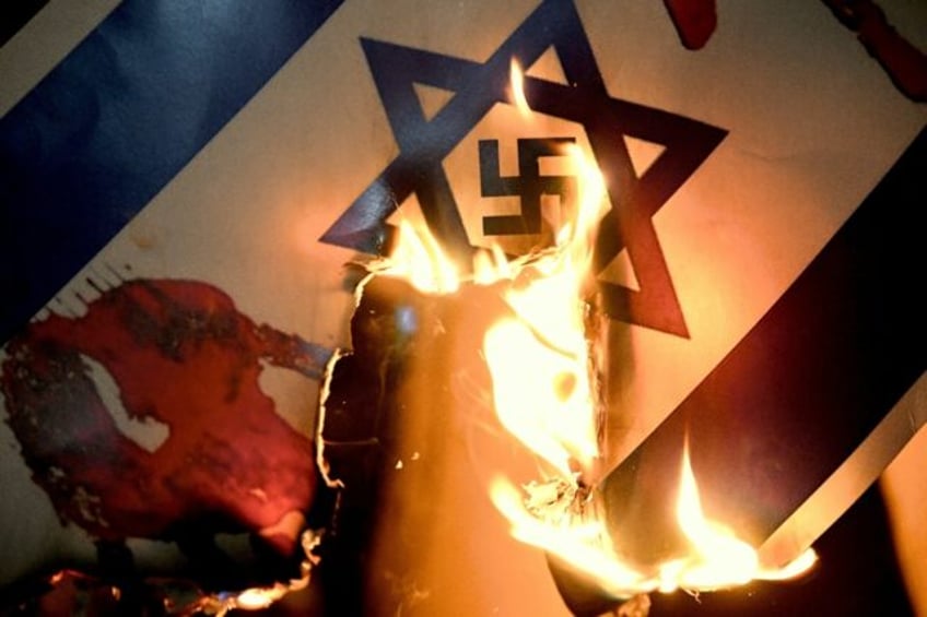 An Israeli flag with a swastika superimposed on the Star of David is burned at a pro-Pales