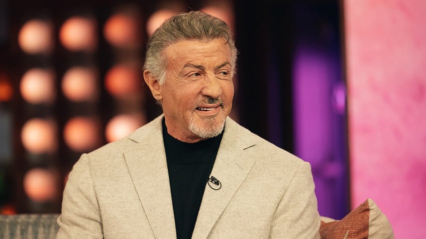 Sylvester Stallone wears a beige suit during an appearance