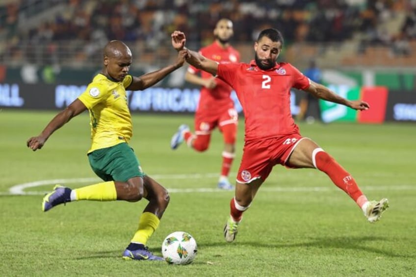 South Africa forward Percy Tau (L) crosses under pressure from Tunisia defender Ali Abdi