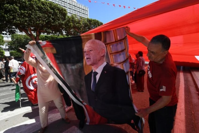 Supporters of Tunisian President Kais Saied ready a portrait for display during a public h