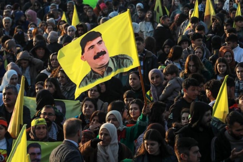 A woman waves a flag bearing a picture of PKK founder Abdullah Ocalan