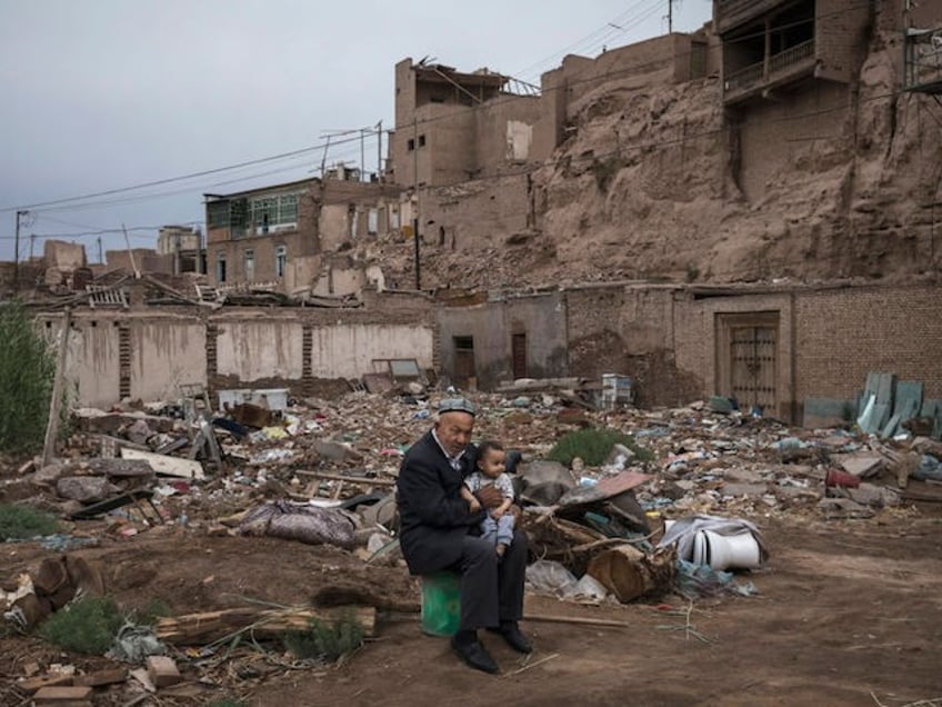 KASHGAR, CHINA - JUNE 28: An ethnic Uyghur man holds his grandson as he sits outside his house in an area waiting development by authorities on June 28, 2017 in the old town of Kashgar, in the far western Xinjiang province, China. Kashgar has long been considered the cultural heart of Xinjiang for the province's nearly 10 million Muslim Uyghurs. At an historic crossroads linking China to Asia, the Middle East, and Europe, the city has changed under Chinese rule with government development, unofficial Han Chinese settlement to the western province, and restrictions imposed by the Communist Party. Beijing says it regards Kashgar's development as an improvement to the local economy, but many Uyghurs consider it a threat that is eroding their language, traditions, and cultural identity. The friction has fueled a separatist movement that has sometimes turned violent, triggering a crackdown on what China's government considers 'terrorist acts' by religious extremists. Tension has increased with stepped up security in the city and the enforcement of measures including restrictions at mosques. (Photo by Kevin Frayer/Getty Images)