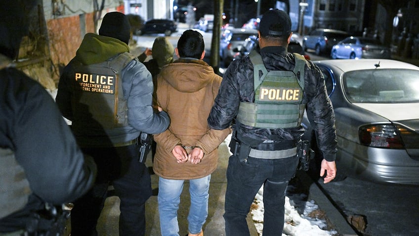 Law enforcement walk with an individual as he was detained in the Bronx during ICE-led operations to apprehend illegal immigrants on Jan. 28 in New York City.