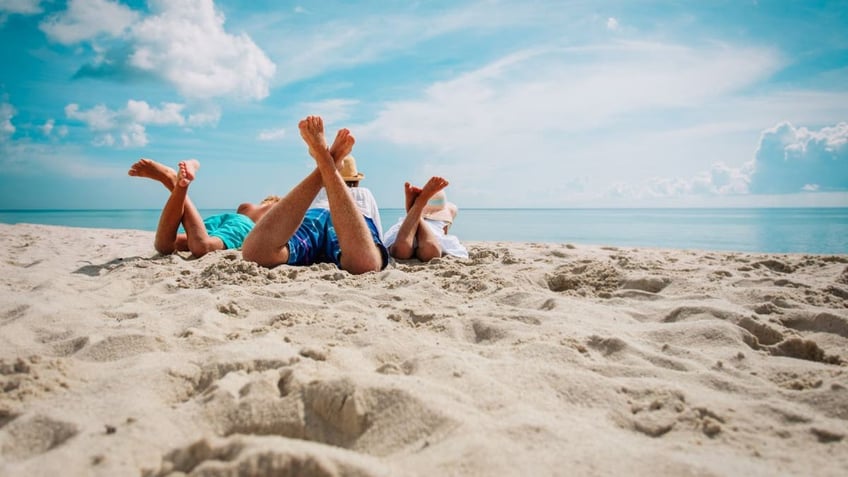 parent relaxing with kids on beach