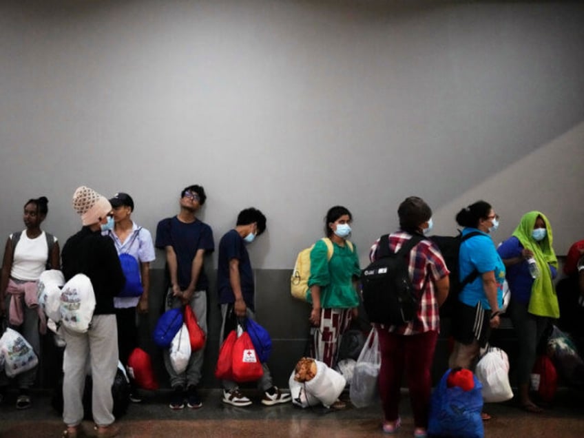 Migrants, mostly from Asian countries, wait for transport to hotels after arriving in Pana