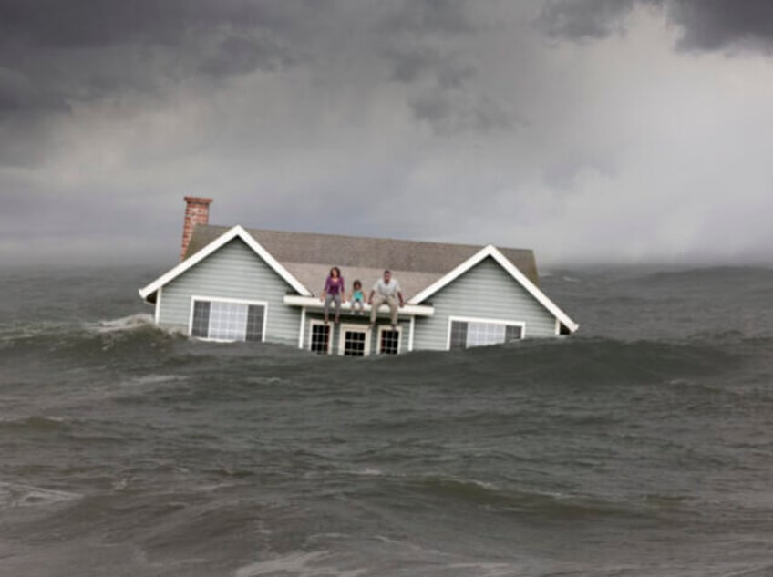 Family sitting on roof of house floating in sea