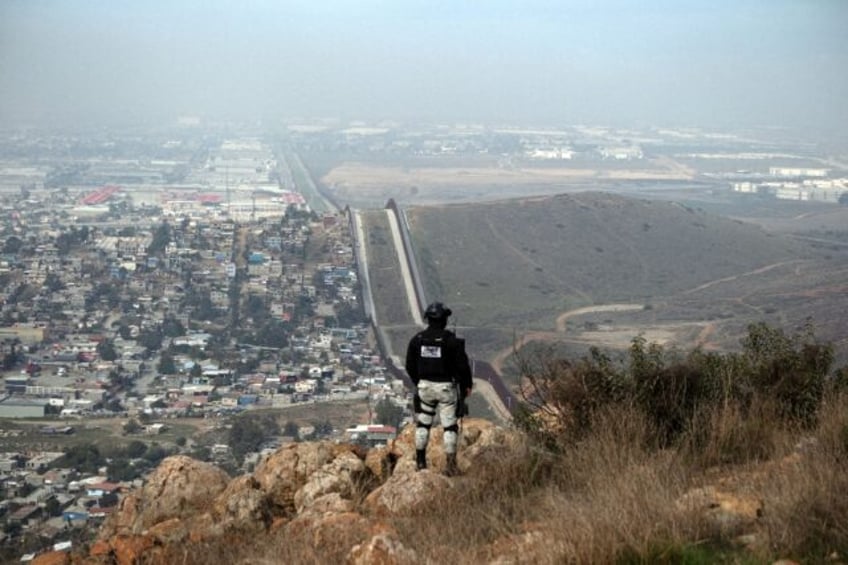 A Mexican National Guard officer patrols a hilly border area on the outskirts of Tijuana
