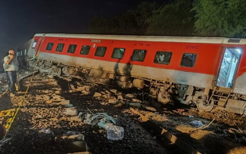 A man stands near the compartment coach of a derailed train during a rescue operation at t