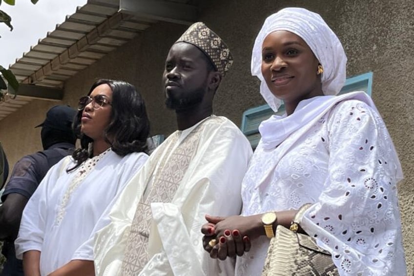 Senegal's president-elect Bassirou Diomaye Faye (C) with his wives Marie Khone Faye (L) an