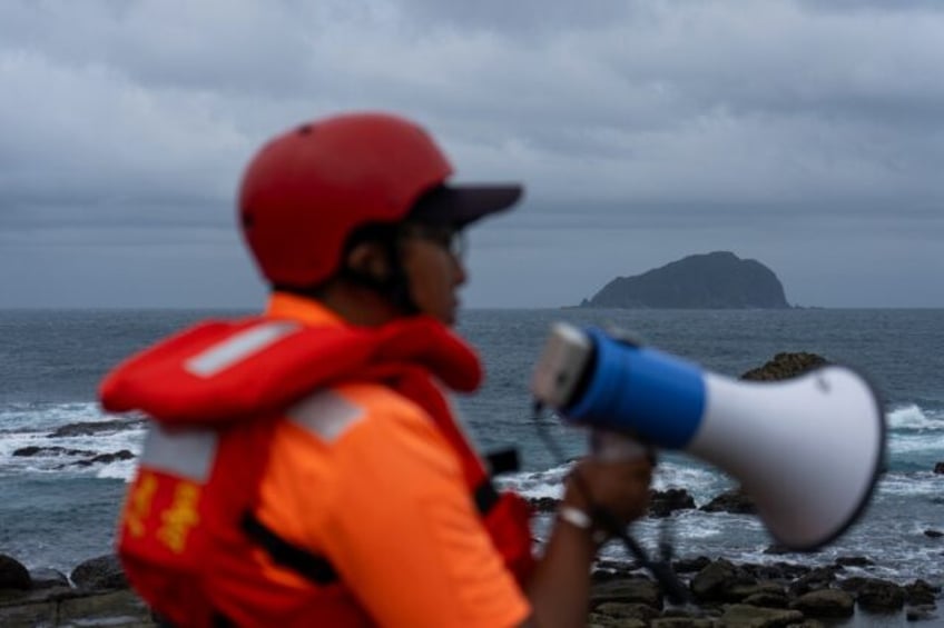 A coast guard member keeps watch for people nearing the coast in Taiwan's Keelung as Typho