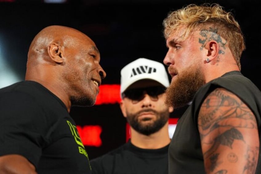 Mike Tyson, left, and Jake Paul, right, stare at each other while promoter Nakisa Bidarian