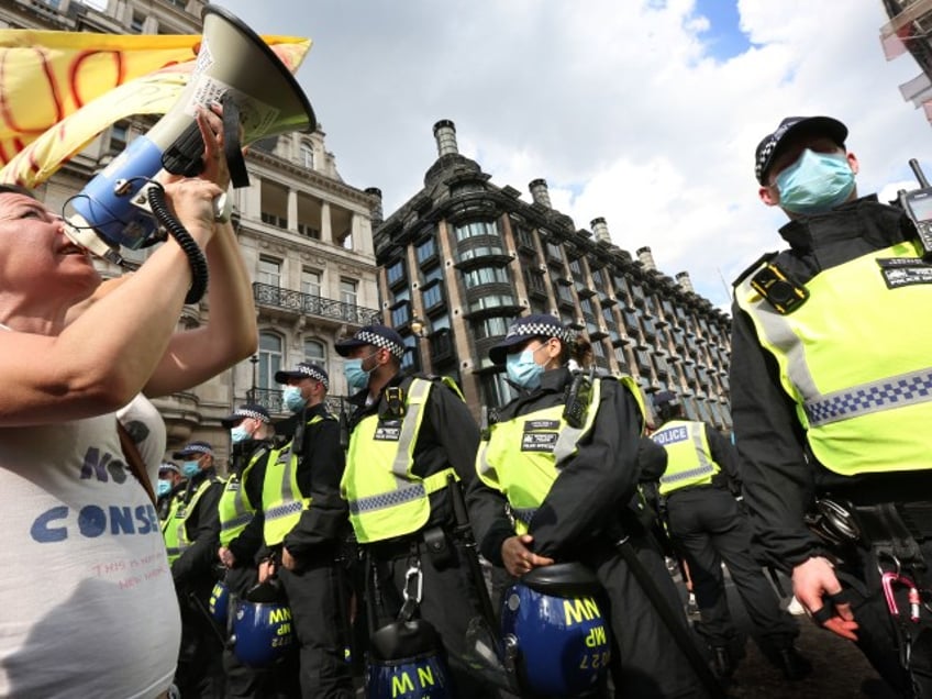 LONDON, ENGLAND - JULY 19: A protester addresses the police line through a megaphone in Parliament Square as part of a freedom demonstration on July 19, 2021 in London, England. Anti-lockdown protests have been a feature of the Coronavirus Pandemic across the UK uniting the anarchist left and anti-establishment right. Many believe the popular conspiracy theory that covid-19 was faked to provide an excuse for systematic regime change. Many are anti-vaxx campaigners. England will press ahead with dropping the last of the lockdown rules today despite a recent surge in Coronavirus cases caused by the Delta variant. (Photo by Martin Pope/Getty Images)