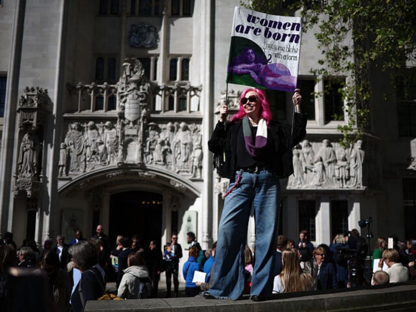 An activist holds a placard reading "Women are born, not some bloke with a form"