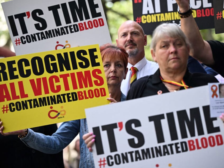 Demonstrators hold placards reading message related to the NHS infected blood scandal as B