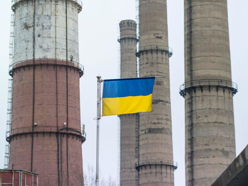 A Ukrainian national flag flies beneath chimneys at the Luhansk thermal power station, operated by DTEK Holdings BV, in Shchastia, Ukraine, on Thursday, March 5, 2015. DTEK, Ukraine's largest privately-owned utility, said it bought coal from South Africa after Russian supplies of the fuel stopped in November. Photographer: Vincent Mundy/Bloomberg …