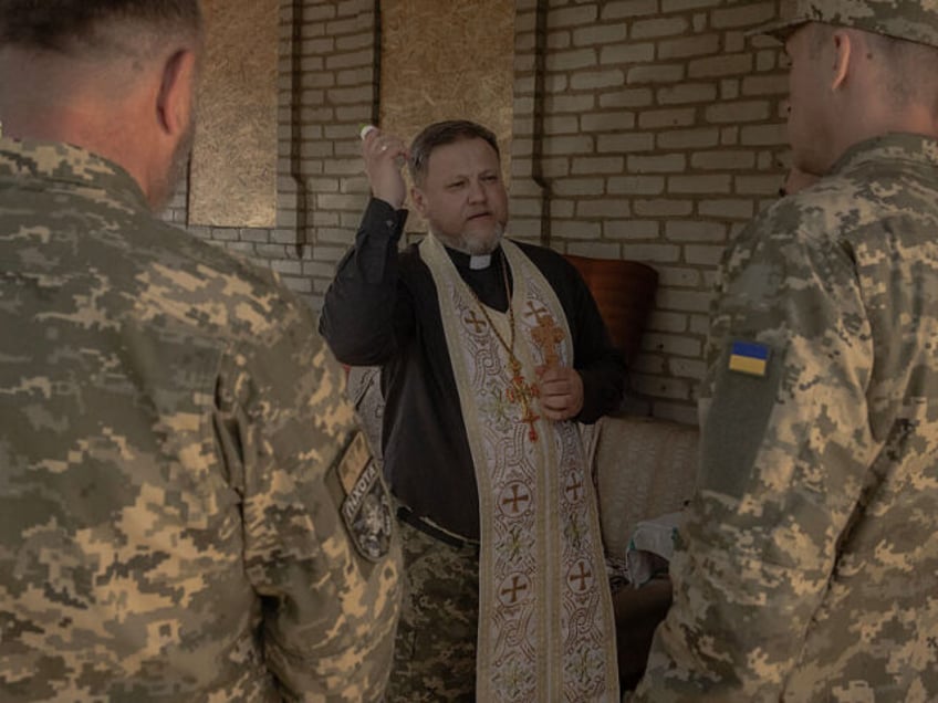 A military chaplain blesses Ukrainian servicemen of the 100th brigade and traditional cake