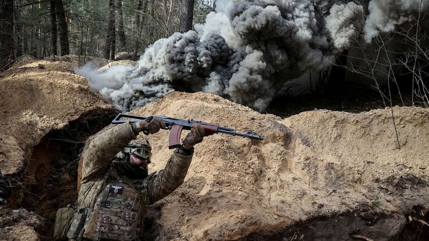 A Ukrainian serviceman of the National Guard shelters in a trench as a dark cloud of gas rolls toward him in during radiation, chemical and biological hazard drills, amid Russia's attack on Ukraine.