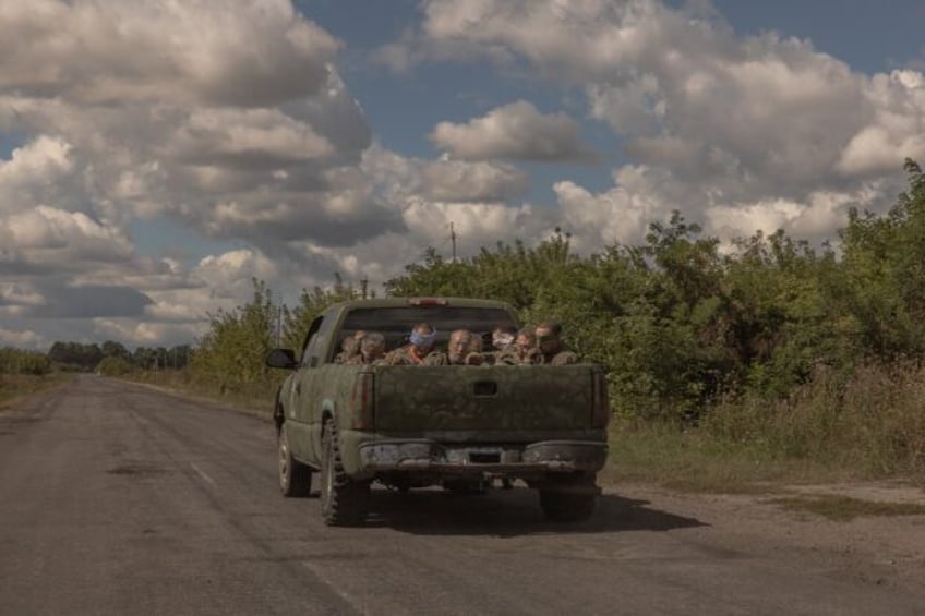 Around 10 blindfolded and bound men in Russian military fatigues being driven in a militar