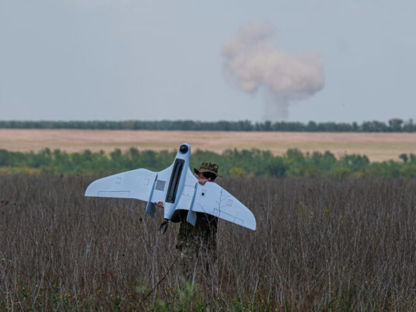 A Ukrainian serviceman of the Ochi reconnaissance unit carries a Furia drone while smoke r