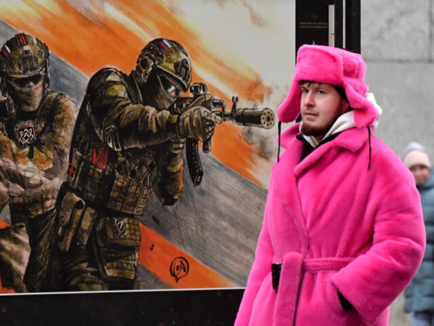 A street artist, calling on people to visit an amusement park, walks past the military-the