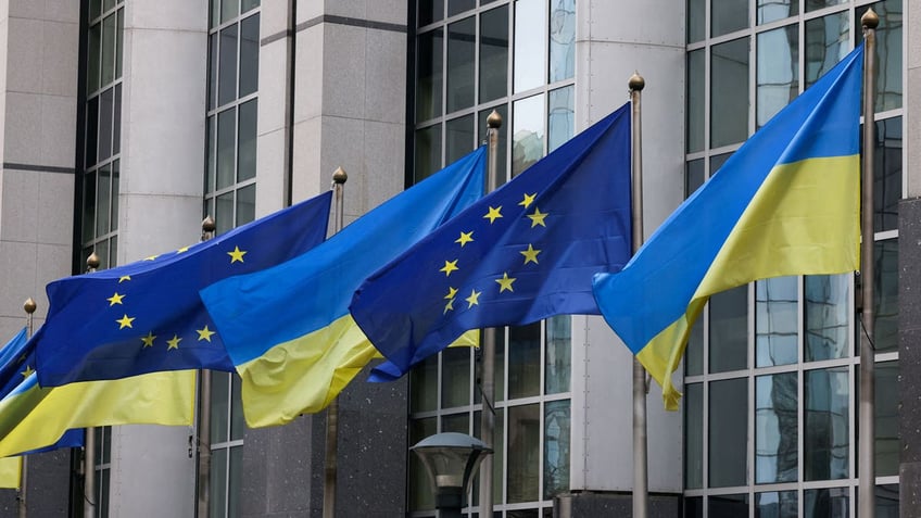Flags of Ukraine fly in front of the EU Parliament building