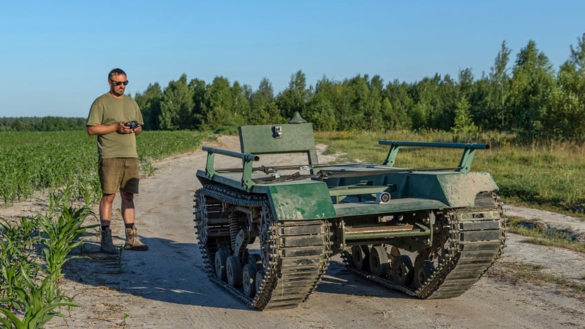 Andrii Denysenko, CEO of design and production bureau "UkrPrototyp," stands beside Odyssey, a 1,750-pound ground drone prototype that looks like a minature tank, at a corn field in northern Ukraine.