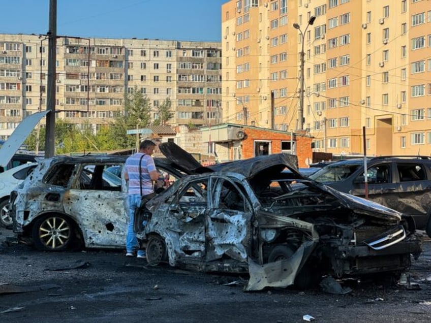 SUMY, UKRAINE - AUGUST 17: A man stands next to the burnt wreckage of cars in a residentia