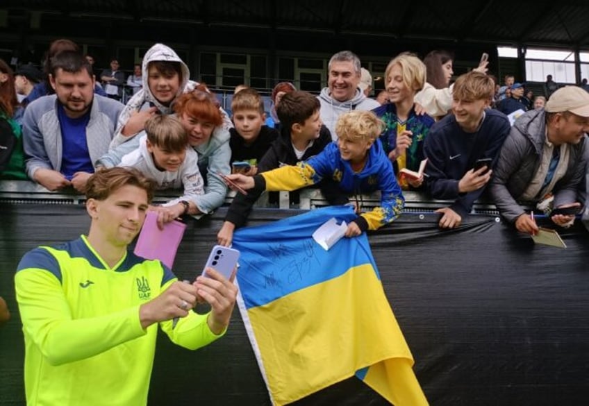 Ukraine defender Illia Zabarnyi poses with fans after a training session before Euro 2024