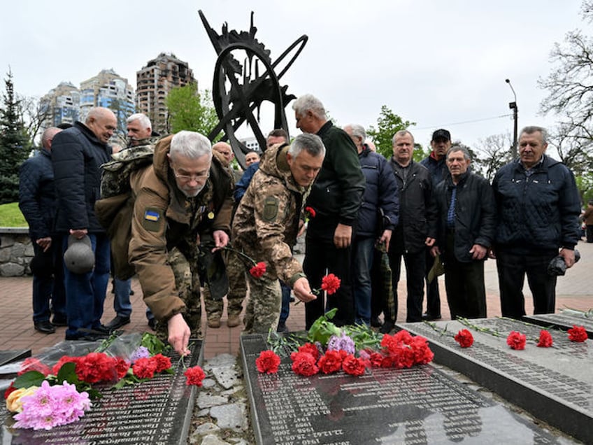 Liquidators of Chernobyl nuclear power plant catastrophe, lay flowers during the commemoration of the victims of the Chernobyl nuclear disaster on the 38th anniversary of the world's worst nuclear accident, at the Chernobyl memorial in Kyiv on April 26, 2024. (Photo by Sergei SUPINSKY / AFP)
