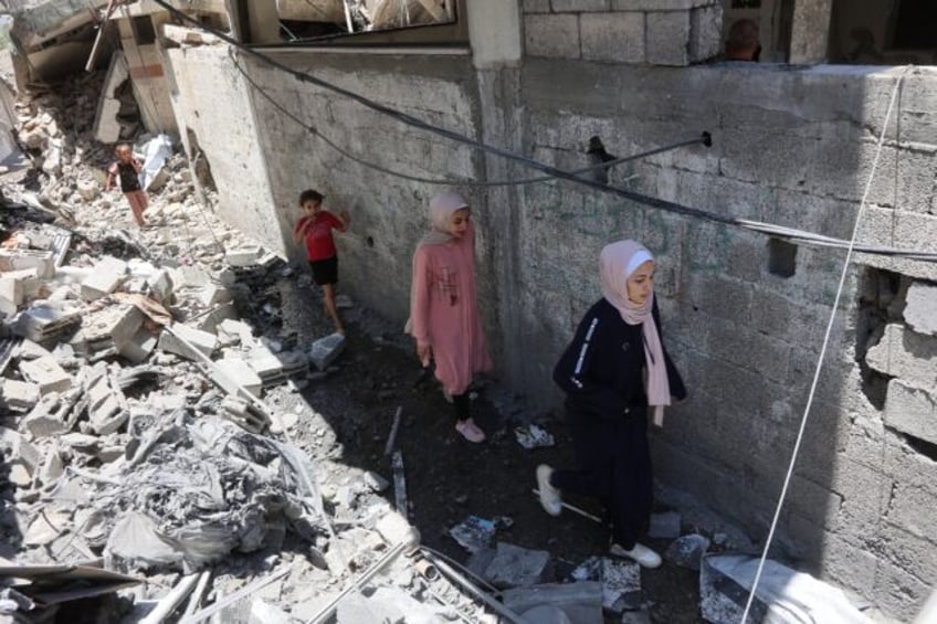 Palestinians children walk amid the rubble of a home that was targeted in an Israeli strik