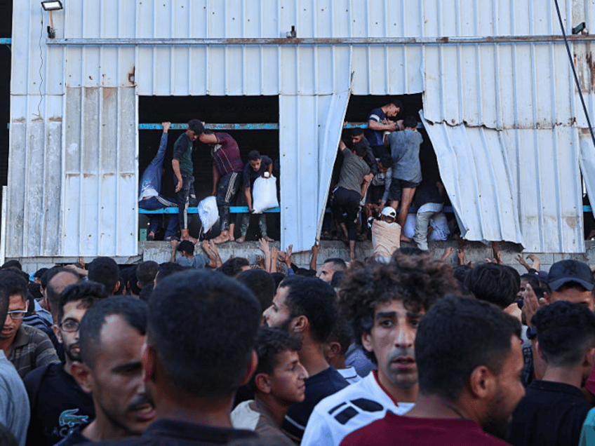 Displaced Palestinians ferry bags of food aid after storming a World Food Programme wareho