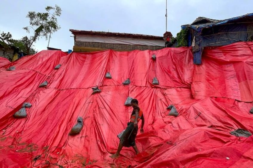 A Rohingya volunteer covers a landslide-affected area with tarpaulin at the Balukhali refu