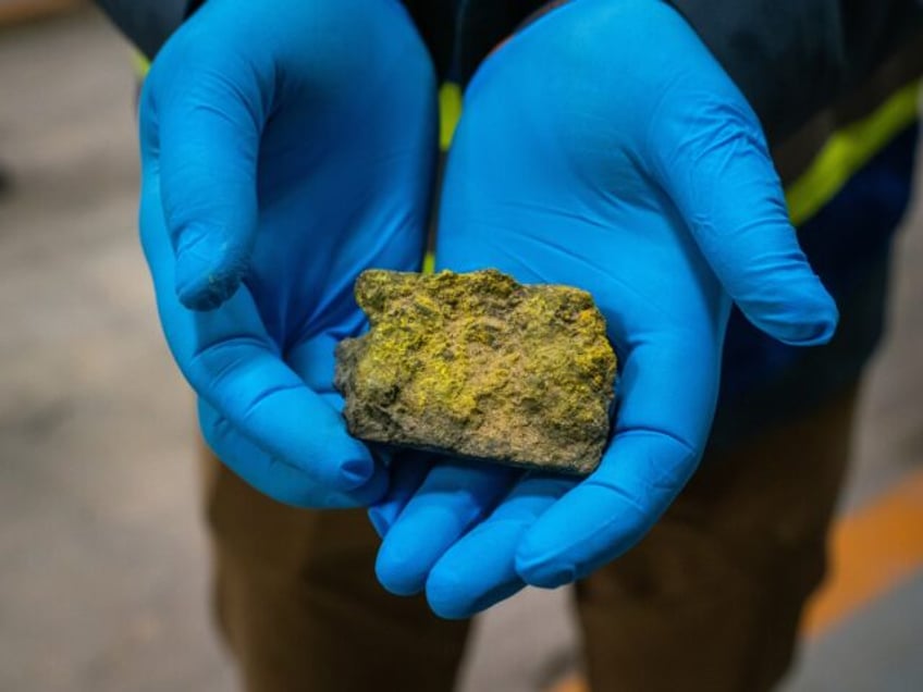 A worker holds a core sample containing oxidized uranium at a core processing facility at