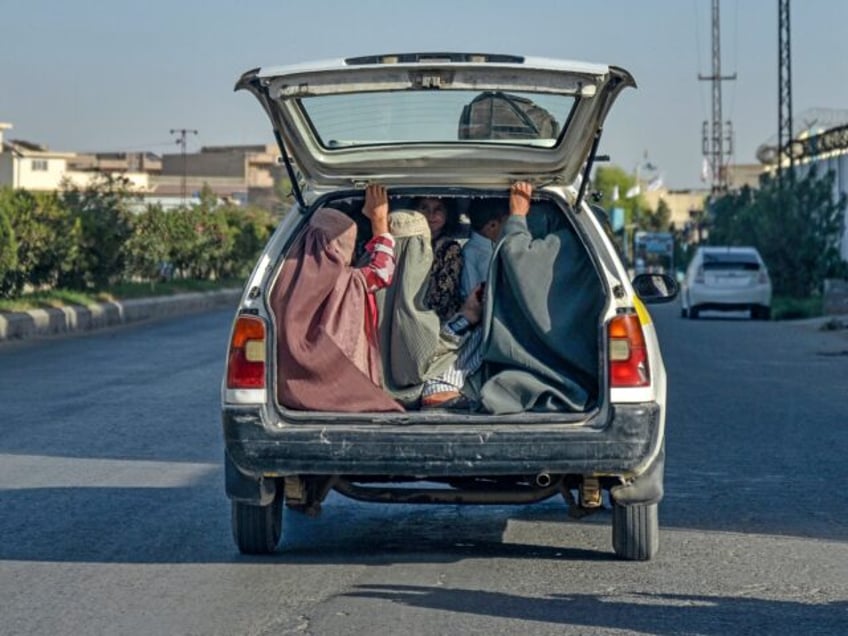 Afghan burqa-clad women travel on the back of a local taxi in Kandahar on September 9, 202