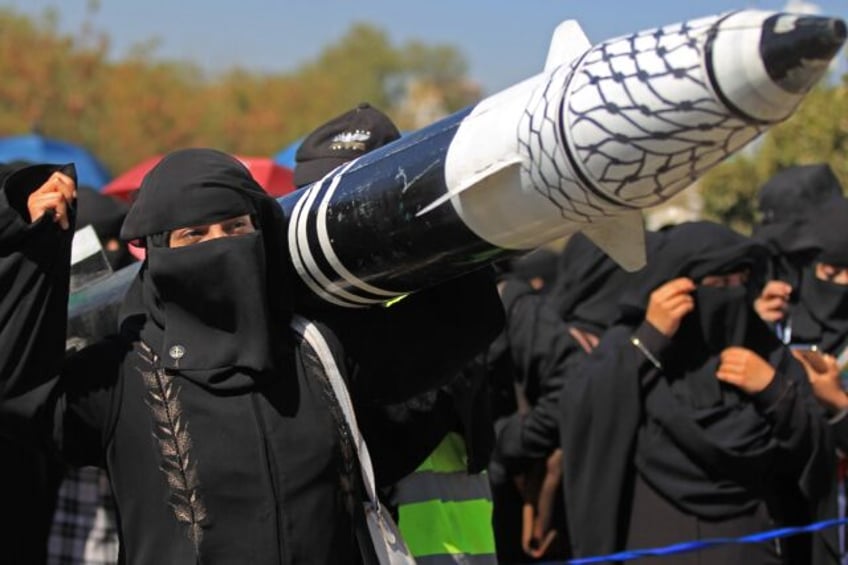 A Yemeni protester holds a mock rocket during an anti-Israel demonstration in the Huthi-co