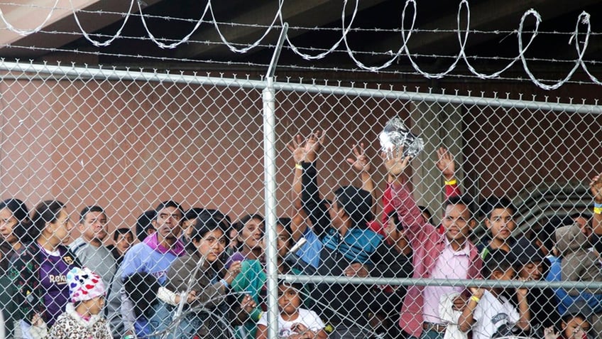migrants behind fence in pen at CBP facility