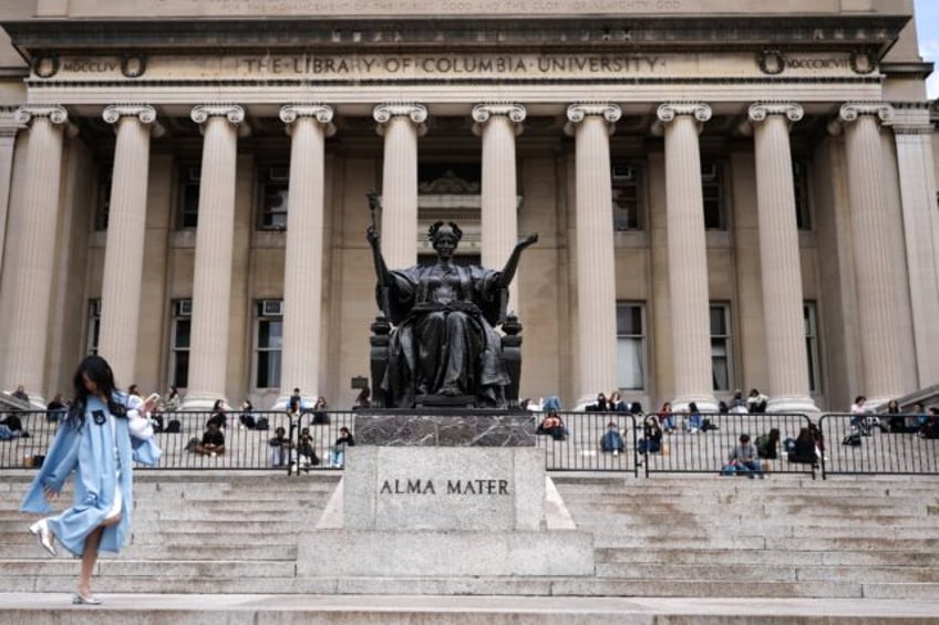 Flanking a famous Alma Mater statue, students sit on the steps of the Low Memorial Library