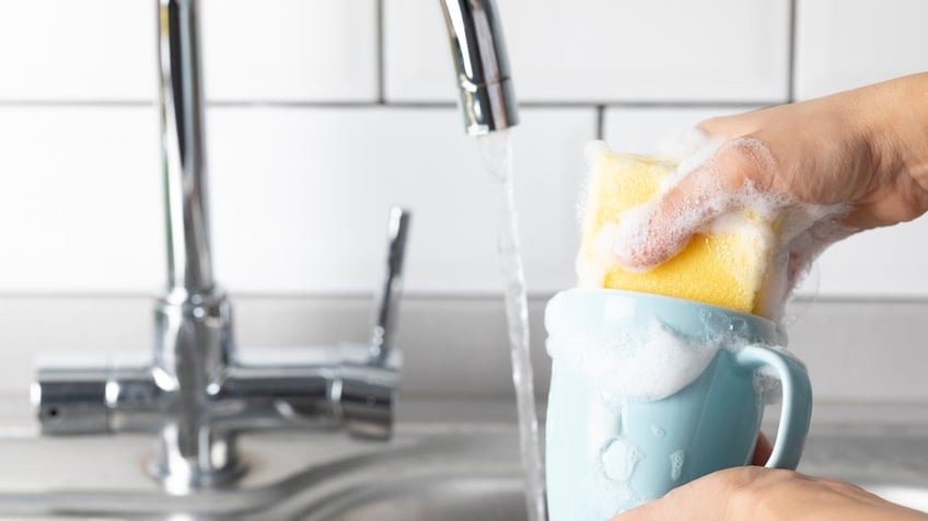 sponge washing mug in kitchen sink