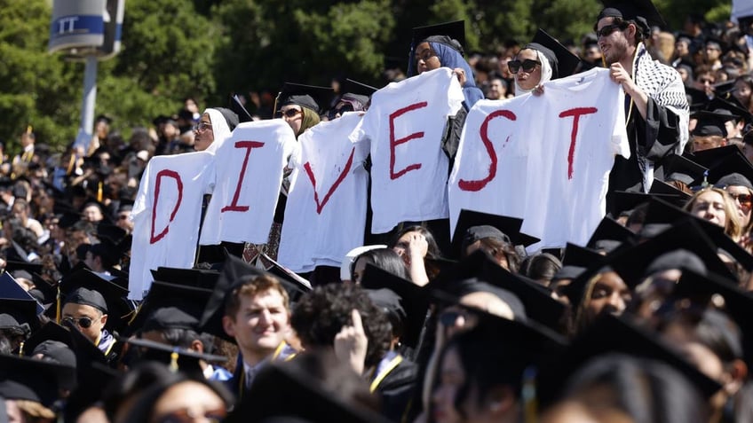 Student holding shirts that read DIVEST