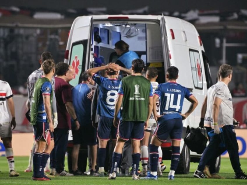 Nacional's defender Juan Manuel Izquierdo (covered) is carried into an ambulance afte