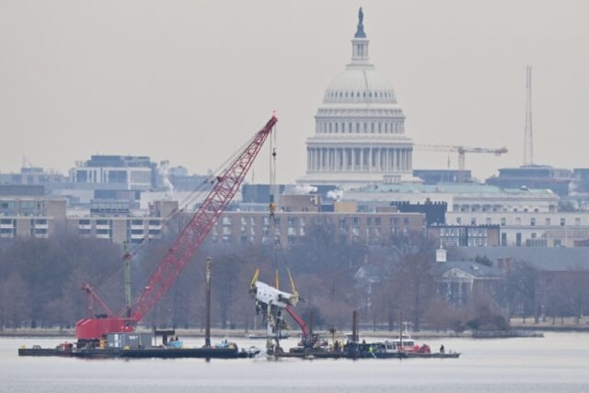 A crane removes wreckage from the Potomac River after an American Eagle airline jet collid