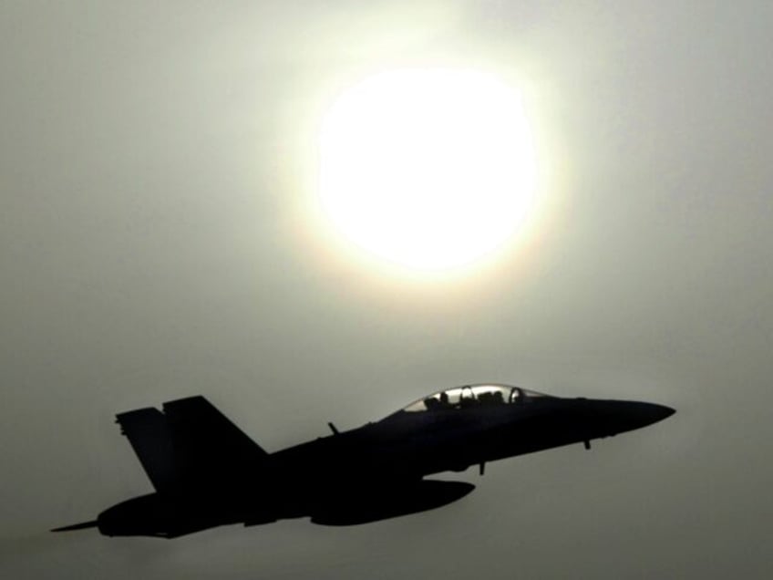 ARABIAN GULF - MARCH 21: An F-18 fighter jet takes off through the dusty sunlight on a mission into Iraq March 21, 2003 at an airbase in the Arabian Gulf as Operation Iraqi Freedom continues with a strategic air campaign. (Photo by Paula Bronstein/Getty Images)