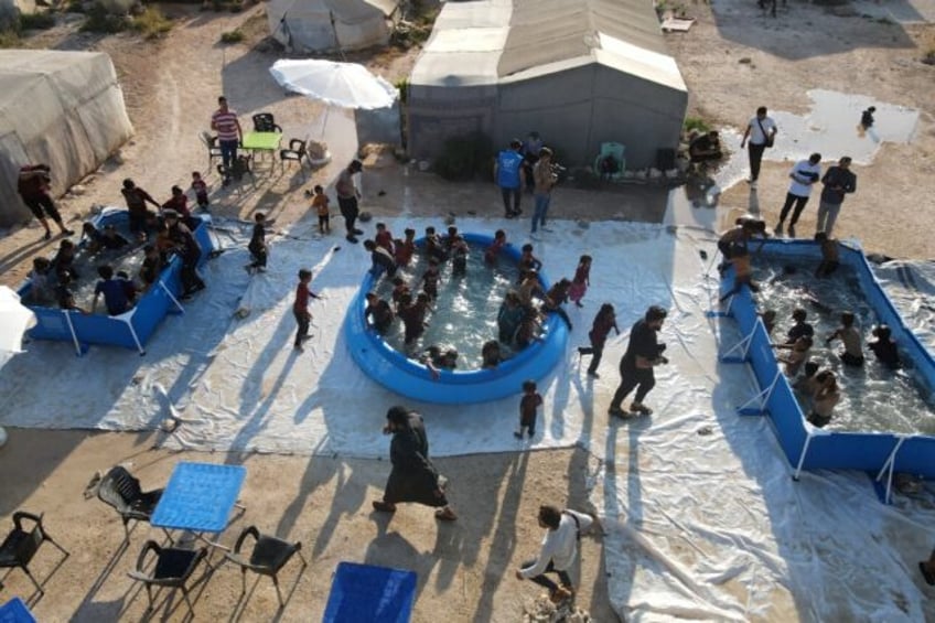 Displaced Syrian children play in swimming pools set up by the Smile Younited charity in t