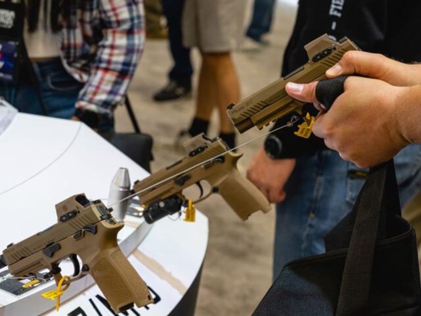 An attendee holds a Sig Sauer M17 handgun during the National Rifle Association (NRA) annu