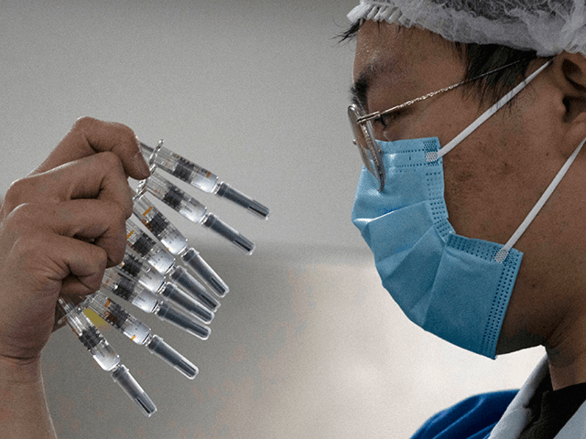 In this Sept. 24, 2020, file photo, a worker inspects syringes of a vaccine for COVID-19 p